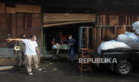 Petugas membantu pedagang mengeluarkan barang dagangan dari lokasi Tempat Penampungan Sementara (TPS) Pasar Turi, Surabaya, Jawa Timur, Senin (21/3/2022). Para pedagang di tempat itu mengosongkan lapaknya menyusul akan dibongkarnya TPS tersebut karena gedung Pasar Turi Baru telah siap ditempati. 