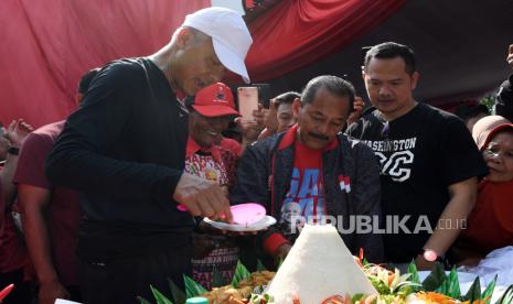 Calon presiden nomor urut 3 Ganjar Pranowo (kiri) memotong tumpeng saat peresmian posko pemenangan Ganjar-Mahfud di Semanggi, Pasar Kliwon, Surakarta, Jawa Tengah, Ahad (24/12/2023). 