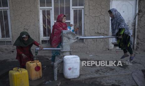 Gadis-gadis mengisi wadah dengan air menggunakan pompa tangan di sebuah kamp untuk pengungsi internal, di Kabul, Afghanistan, Senin, 15 November 2021.