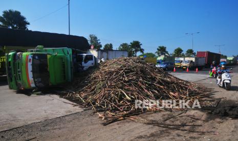 Pengendara sepeda motor melintas di samping truk yang mengalami kecelakaan tunggal di jalan pantura lingkar selatan Desa Ngembal Kulon, Kudus, Jawa Tengah, Rabu (17/5/2023). Mobil truk bernopol K 1467 SP mengangkut Tebu dari arah Sragen menuju Pati itu terguling akibat As roda patah sehingga menyebabkan sedikit ketersendatan arus lalu-lintas. 