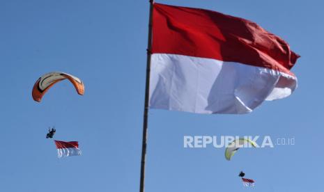 Penerbang paralayang mengibarkan bendera merah putih di Badung, Bali, Selasa (17/8/2021). Pengibaran bendera di udara kawasan Bali Selatan tersebut dilakukan untuk memeriahkan peringatan HUT ke-76 Kemerdekaan RI sekaligus untuk mensosialisasikan kegiatan olahraga dirgantara kepada masyarakat. 