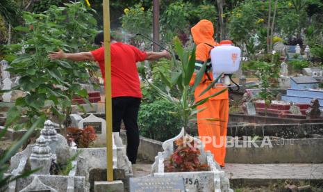 Petugas kepolisian menggunakan alat pelindung diri (ADP) menyemprotkan disinfektan kepada kerabat keluarga usai memakamkan Pasien Dalam Pengawasan (PDP) COVID-19 di Medan, Sumatera Utara, Senin (30/3/2020). Provinisi Sumut mencatat total kasus terkait COVID-19 yang meninggal di Kota Medan berjumlah 4 orang yakni dua berstatus pasien positif dan dua lainnya berstatus PDP