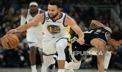 Stephen Curry dari Golden State Warriors merebut bola lepas di depan George Hill dari Milwaukee Bucks selama paruh pertama pertandingan bola basket NBA Selasa, 13 Desember 2022, di Milwaukee.