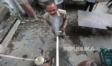 Personel polisi India menghirup uap herbal yang keluar dari pipa yang terhubung ke pressure cooker, sebagai tindakan pencegahan terhadap Covid-19 di luar kantor polisi di Ghaziabad, Uttar Pradesh, India, 03 Juni 2021.