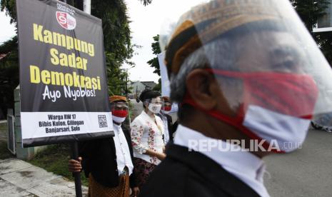 Warga Bibis Kulon, Gilingan, Solo berbusana adat dan mengusung poster bertuliskan Kampung Sadar Demokrasi Ayo Nyoblos di kampung setempat, Solo, Jawa Tengah, Kamis (3/12/2020). Aksi tersebut untuk mengajak masyarakat Solo menggunakan hak pilih dalam Pilkada 2020. 