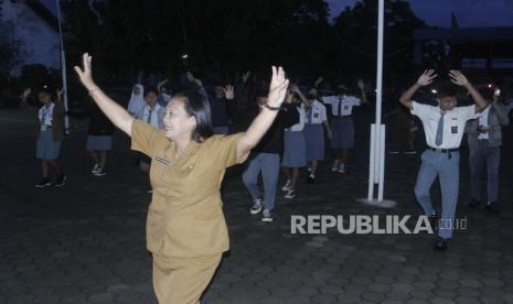 Seorang ibu guru  sekolah menengah atas (SMA) memandu gerakan senam sebekum masuk kelas  di SMA Negeri I Kupang, di Kota Kupang, NTT, Senin (6/3/2023). Pemerintah provinsi NTT merubah kebijakan jam masuk sekolah untuk SMA/SMK di Kota Kupang, dari semula 05.00 WITA menjadi 05.30 WITA dan pulang sekolah 10.30 WITA setelah banyaknya kritikan dan masukan dari masyarakat.  