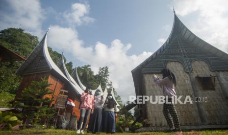 Pengunjung berfoto dengan latar Rumah Gadang, Nagari Sumpu, Kabupaten Tanah Datar, Sumatera Barat, Ahad (29/8). Juru bicara Pemerintah untuk Penanganan Covid-19 Wiku Adisasmito menekankan agar pembukaan kegiatan pariwisata harus dengan prinsip kehati-hatian. 