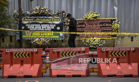 Anggota kepolisian berjalan di depan karangan bunga di Mapolsek Astana Anyar,  Jalan Astana Anyar, Kota Bandung, Kamis (8/12/2022). Markas Kepolisian Sektor (Mapolsek) Astana Anyar ditutupi pagar seng pascaledakan bom bunuh diri yang terjadi pada Rabu (7/12/2022). Selain itu, seluruh pelayanan di Mapolsek Astana Anyar dialihkan sementara ke Polrestabes Bandung. Republika/Abdan Syakura