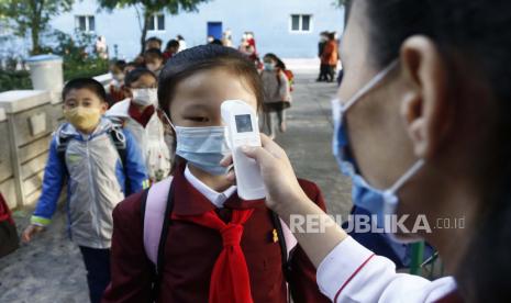  FILE - Seorang guru mengukur suhu tubuh seorang siswi untuk membantu mengekang penyebaran virus corona sebelum memasuki Sekolah Dasar Kim Song Ju di Distrik Pusat di Pyongyang, Korea Utara, Rabu, 13 Oktober 2021. Sebelum mengakui kasus COVID-19 domestik , Kamis, 12 Mei 2022, Korea Utara menghabiskan 2 1/2 tahun menolak tawaran vaksin dari luar dan dengan teguh mengklaim bahwa sistem sosialisnya yang unggul melindungi 26 juta orangnya dari “virus jahat” yang telah membunuh jutaan orang di seluruh dunia.