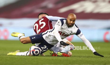 Lucas Moura dari Tottenham jatuh saat dia dijegal oleh Morgan Sanson dari Aston Villa, kiri, pafa pertandingan sepak bola Liga Premier Inggris antara Aston Villa dan Tottenham Hotspur di Villa Park di Birmingham, Inggris, Senin (22/3) dini hari WIB. 