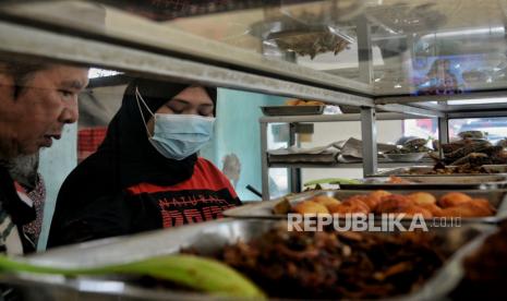 Pekerja melayani pengunjung yang hendak makan di salah satu rumah makan. Meski harga bahan-bahan pokok meroket tapi harga makanan tak bisa langsung ikut naik. Ilustrasi.