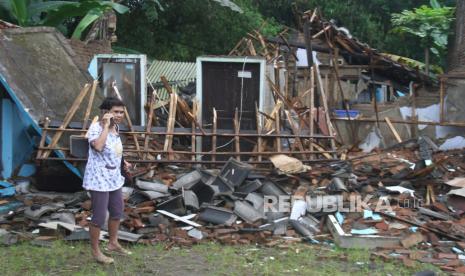 Seorang warga menelepon di depan rumahnya yang hancur akibat gempa di Majangtengah, Malang, Jawa Timur, Ahad (11/4/2021). Badan Nasional Penanggulangan Bencana (BNPB) melaporkan sedikitnya 1.189 unit rumah rusak akibat gempa bermagnitudo 6,1 yang mengguncang kawasan Malang dan sekitarnya. 