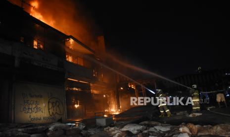 Petugas Pemadam Kebakaran dibantu warga memadamkan api yang menghanguskan bangunan di kawasan Senen, Jakarta, Kamis (8/10/2020) malam. Menurut warga sejumlah bangunan toko dan bekas gedung bioskop Megaria tersebut dibakar massa saat berunjuk rasa menolak pengesahan Omnibus Law UU Cipta Kerja.