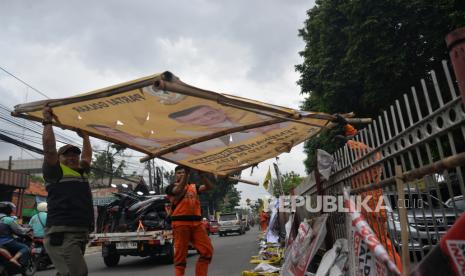 Petugas Satpol PP menertibkan alat peraga kampanye (APK) yang  berada di pembatas jalan di Jalan Raya Bogor, Kramat Jati, Jakarta, Senin (29/1/2023). Petugas Satpol PP bersama unsur terkait lainnya menertibkan APK yang melanggar ketentuan yang bertujuan untuk menjaga kebersihan dan estetika kota.