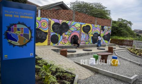 Sejumlah warga menulis di salah satu dinding di area taman Ruang Curhat Curug Tilu usai diresmikan di Jalan Sukamulya, Sukajadi, Kota Bandung, Jumat (1/4/2022). Pemerintah Kota Bandung meresmikan taman Ruang Curhat Curug Tilu yang merupakan ruang terbuka hijau dengan pemandangan air terjun (curug) di tengah kota dan fasilitas dinding yang dapat digunakan warga untuk menuliskan harapan, keluh kesah atau curhat. Foto: Republika/Abdan Syakura