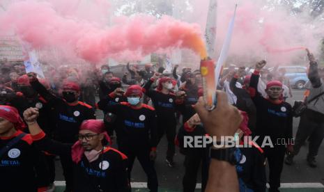 Sejumlah buruh menyalakan suar saat melaksanakan aksi di Balai Kota DKI Jakarta, Rabu (20/7/2022). Pada aksi tersebut mereka menuntut Gubernur DKI Jakarta Anies Baswedan untuk melakukan banding terhadap putusan PTUN yang menurunkan nilai UMP DKI Jakarta tahun 2022 dari Rp 4.641.854 menjadi Rp 4.573.845 dan mendesak pengusaha tetap membayar upah sebesar Rp 4.641.854 selama belum ada putusan di tingkat banding. Republika/Putra M. Akbar