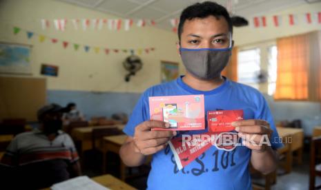 Warga menunjukan buku tabungan Bank DKI dan kartu debit usai mengambil bantuan sosial tunai (BST) di SMPN 3, Jakarta, Selasa (26/1). 