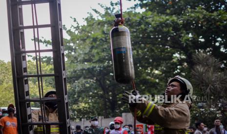 Petugas Suku Dinas Penanggulangan Kebakaran dan Penyelamatan (Gulkarmat) mangikat tabung oksigen saat melakukan proses evakuasi kebakaran Gedung Cyber, Jakarta, Kamis (2/12). Sebanyak 22 unit mobil pemadam dan 100 personel dikerahkan untuk memadamkan api yang diduga akibat konsleting listrik dan sebanyak tiga orang menjadi korban, dua diantaranya dinyatakan meninggal. Republik/Thoudy Badai