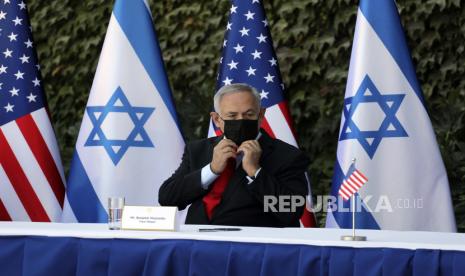  Perdana Menteri Israel Benjamin Netanyahu menyesuaikan masker wajahnya saat upacara penandatanganan amandemen serangkaian perjanjian kerja sama ilmiah dengan Duta Besar AS untuk Israel David Friedman, di Universitas Ariel, di pemukiman Tepi Barat Ariel, Rabu, 28 Oktober 2020. Amerika Serikat dan Israel mengubah perjanjian pada Rabu untuk memasukkan lembaga-lembaga Israel di Tepi Barat, sebuah langkah yang semakin mengaburkan status permukiman yang secara luas dianggap ilegal menurut hukum internasional.