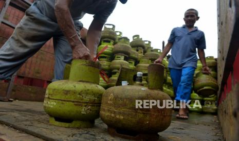 Pekerja menurunkan tabung gas LPG 3 kilogram bersubsidi di salah satu agen. 