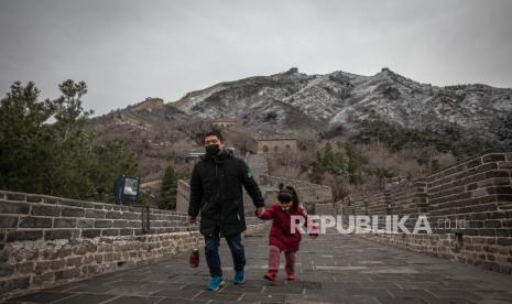  Seorang pria dengan seorang gadis muda mengenakan masker berjalan di Tembok Besar Badaling yang hampir kosong, di Beijing, Cina, 26 Maret 2020 (dikeluarkan 27 Maret 2020). China telah membuka kembali bagian Badaling, salah satu bagian turis paling terkenal di Tembok Besar yang ditutup karena wabah virus corona. Sementara kasus baru Covid-19 di China telah menurun, penyakit ini sekarang menyebar secara dramatis ke seluruh dunia.. Sejauh ini telah menewaskan lebih dari 22.000 orang di seluruh dunia. EPA-EFE / ROMAN PILIPEY