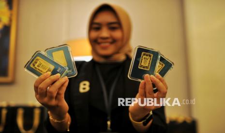 Model menunjukan replika emas batangan BSI saat peluncuran BSI Gold di Jakarta, Kamis (28/11/2024).