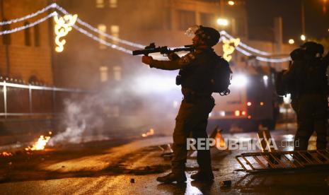 Seorang petugas polisi Israel mengarahkan senapannya ke arah demonstran Palestina selama bentrokan di gerbang Damaskus di luar Kota Tua Yerusalem, Sabtu, 8 Mei 2021.