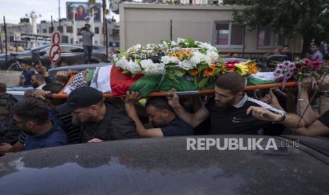 Pelayat Palestina membawa jenazah Shireen Abu Akleh keluar dari kantor Al Jazeera setelah teman dan kolega memberikan penghormatan, di kota Ramallah, Tepi Barat, Rabu, 11 Mei 2022. 