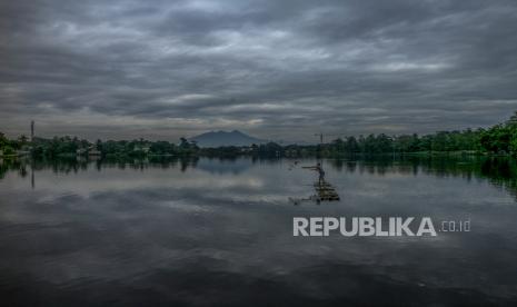 Warga menjaring ikan di Situ Cikaret dengan latar belakang awan mendung di Cibinong, Kabupaten Bogor, Jawa Barat.