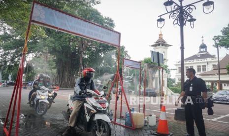 Warga melewati portal disinfektan otomatis yang dipasang depan pintu masuk komplek Balaikota Solo, Jawa Tengah, Jumat (27/3/2020). Pemerintah Kota Solo mewajibkan siapapun yang masuk untuk disterilisasi dengan melewati portal tersebut guna mengantisipasi penyebaran Virus Corona atau COVID-19 di lingkungan Balaikota