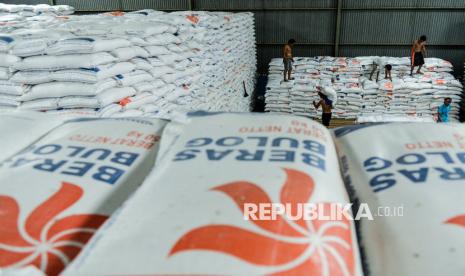 Pekerja memanggul karung berisi beras di gudang Perum Bulog Umbul Tengah, Kota Serang, Banten.