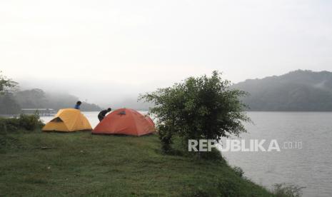 Pengunjung berkemah di tepian Waduk Sermo, Kokap, Kulon Progo, DI Yogyakarta, Ahad (11/4/2021).  Kawasan wisata alam yang menjadi destinasi wisata pendukung bandara baru Yogyakarta International Airport tersebut menawarkan atraksi wahana air dan berkemah di pinggir waduk. 