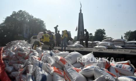 Sejumlah pekerja mengangkat beras Bulog dari jalanan ke atas truk saat evakuasi di kawasan Tugu Kujang, Kota Bogor, Jawa Barat, Rabu (30/8/2023). 