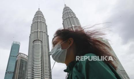 Seorang wanita yang memakai masker wajah berjalan di Menara Kembar Petronas di Kuala Lumpur, Malaysia. Sebelumnya pemerintah Malaysia mengkhawatirkan isu penyitaan aset milik Petronas di Sudan. Ilustrasi. 