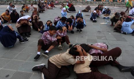 Sejumlah siswa sekolah melindungi kepala saat mengikuti simulasi gempa dan tsunami di objek wisata Pantai Padang, Sumatera Barat, Sabtu (5/11/2022). Simulasi yang digelar untuk memperingati Hari Kesadaran Tsunami Sedunia tersebut bertujuan untuk meningkatkan kewaspadaan warga di pesisir Sumatera Barat terhadap bencana tsunami. 