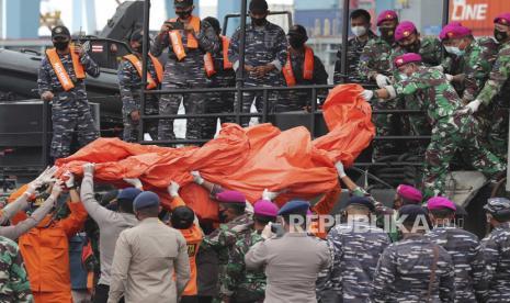 Personel TNI AL dan polisi membawa terpal berisi puing-puing yang ditemukan dari perairan lepas Pulau Jawa di sekitar tempat sebuah jet penumpang Sriwijaya Air jatuh, di Pelabuhan Tanjung Priok di Jakarta, Indonesia, Minggu, 10 Januari 2021. Penyelam Indonesia pada hari Minggu menemukan beberapa bagian dari bangkai pesawat Boeing 737-500 di Laut Jawa, sehari setelah pesawat yang membawa puluhan orang itu jatuh tak lama setelah lepas landas dari Jakarta.