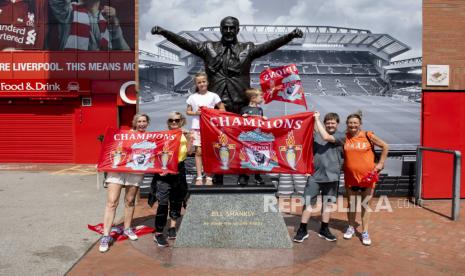 Penggemar Liverpool FC berpose untuk foto di sebelah patung yang menggambarkan mantan pelatih legendaris Skotlandia Bill Shankly di luar stadion Anfield di Liverpool, Inggris, 26 Juni 2020. Liverpool dinobatkan sebagai juara Liga Premier untuk pertama kalinya dalam tiga dekade setelah Chelsea FC mengalahkan Manchester City FC 2-1 pada malam 25 Juni. Kegagalan Man City untuk memenangkan duel krusial ini secara matematis menyerahkan gelar liga Inggris ke klub Liverpudlian yang dipimpin oleh manajer Jerman Juergen Klopp.