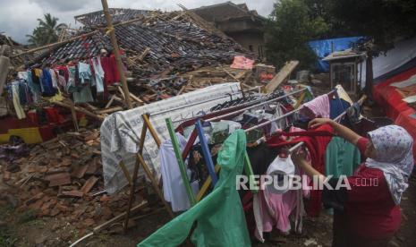 Seorang warga menjemur baju di sekitar reruntuhan rumahnya yang hancur akibat gempa bumi di Benjot, Kabupaten Cianjur, Jawa Barat, Jumat (25/11/2022). Masa tanggap darurat penanganan gempa bumi di Kabupaten Cianjur ditetapkan selama 30 hari sejak Senin (21/11/2022).  PMI Persilakan Warga Cianjur Ambil Bantuan Secara Mandiri