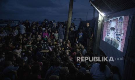 Anak-anak berkumpul di bioskop darurat yang didirikan di antara tenda-tenda kamp pengungsi Rafah, Jalur Gaza bagian selatan, 28 April 2024. 