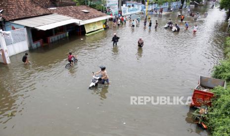 Pengendara sepeda motor mendorong kendaraannya saat menerobos jalan yang tergenang banjir di kawasan jalan raya Gempol, Pasuruan, Jawa Timur, Senin (2/11/2020).  Hujan lebat yang turun beberapa hari terakhir dan jebolnya tanggul di kawasan tersebut mengakibatkan banjir dengan ketinggian 80 cm sampai satu meter. 