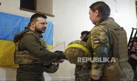 Dalam foto yang disediakan oleh Kantor Pers Kepresidenan Ukraina pada hari Ahad, 29 Mei 2022, Presiden Ukraina Volodymyr Zelenskyy, kiri, memberikan penghargaan kepada seorang prajurit wanita saat ia mengunjungi wilayah Kharkiv yang dilanda perang. Pengadilan Ukraina memvonis dua tentara Rusia dengan hukuman 11 setengah tahun penjara atas penembakan di Ukraina timur.