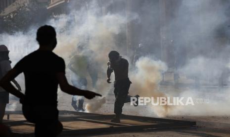  Pengunjuk rasa anti-pemerintah bentrok dengan polisi anti huru hara dan lari dari gas air mata, ketika mereka mencoba mencapai gedung Parlemen, selama protes terhadap para elit politik dan pemerintah, di Beirut, Lebanon, Sabtu, 8 Agustus 2020. Sekelompok orang Pengunjuk rasa Lebanon termasuk pensiunan perwira militer telah menyerbu gedung Kementerian Luar Negeri di ibu kota Beirut sebagai bagian dari protes menyusul ledakan besar-besaran minggu ini. 