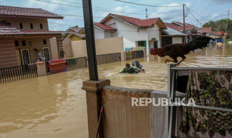 Seorang warga menggunakan kasur karet saat akan keluar dari Perumahan Graha Fauzan Asri yang terendam banjir akibat luapan Sungai Sail di Pekanbaru, Riau, Senin (29/3/2021).  Hujan deras yang mengguyur Kota Pekanbaru beberapa hari belakangan ini mengakibatkan sungai-sungai meluap dan merendam pemukiman warga hingga ketinggian air mencapai 1,5 meter di beberapa lokasi, dan puluhan Kepala Keluarga terpaksa mengungsi sementara ke tempat yang lebih aman. 