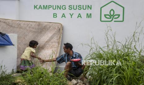 Seorang anak memberikan minum untuk orang tuanya diluar tenda yang didirikan di depan Gerbang Kampung Susun Bayam, Tanjung Priok, Jakarta Utara, Rabu (30/11/2022). Tenda tersebut didirikan sebagai bentuk protes warga untuk menuntut kejelasan kapan bisa menghuni Kampung Susun Bayam yang seharusnya diperuntukkan bagi 135 warga eks Kampung Bayam yang terdampak pembangunan Jakarta International Stadium. Republika/Putra M. Akbar.