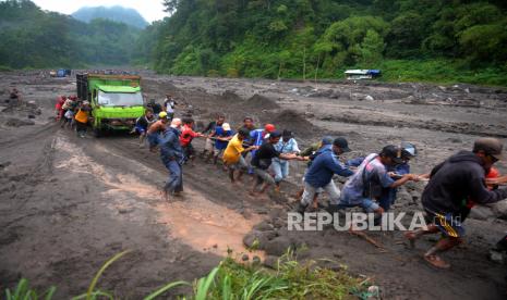 Warga membantu evakuasi truk yang terguling imbas banjir lahar dingin di Kali Boyong, Sleman, Yogyakarta.