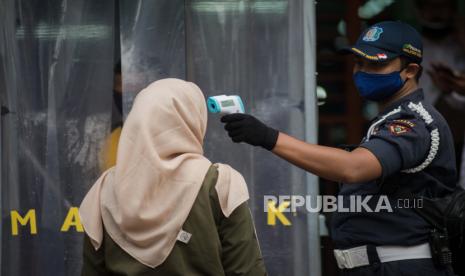 Petugas mengecek suhu tubuh pengunjung pasar saat akan berbelanja di Pasar Perumnas Klender, Jakarta, Senin (15/6). Satpol PP DKI Jakarta mengawasi penerapan protokol kesehatan di pasar tradisional.