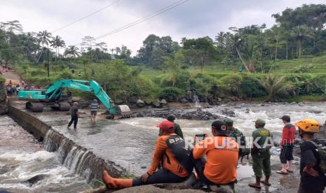 Petugas dan warga melihat alat berat yang membersihkan sumbatan cekdam di bawah Jembatan Cidugaleun, Kecamatan Cigalontang, Kabupaten Tasikmalaya, Senin (8/5/2023). Cekdam itu akan digunakan untuk jalur alternatif sementara karena oprit Jembatan Cidugaleun ambruk pada Ahad (7/5/2023) sore. 