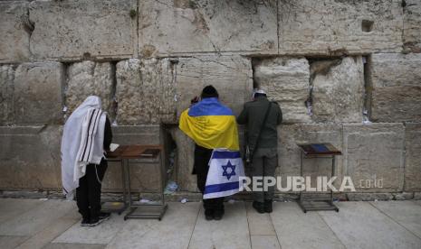 File -- Seorang pria Yahudi ultra-Ortodoks yang dibungkus dengan bendera nasional Ukraina dan Israel berdoa di Tembok Barat,di Kota Tua Yerusalem, Jumat, 4 Maret 2022. Menteri Luar Negeri Israel Eli Cohen pada Kamis (16/2/2023) mengatakan, Israel berkomitmen terhadap kedaulatan Ukraina. 