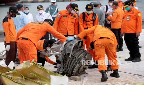 Anggota Badan Pencarian dan Penyelamatan Nasional (BASARNAS) memeriksa puing-puing pesawat Sriwijaya Air penerbangan SJ 182, yang ditemukan dari lokasi kecelakaan di perairan Jakarta, di pelabuhan Tanjung Priok di Jakarta, Indonesia, 19 Januari 2021. Penerbangan Sriwijaya Air SJ182 jatuh ke laut lepas pantai Jakarta pada tanggal 09 Januari 2021 sesaat setelah lepas landas dari Bandara Internasional Jakarta dalam perjalanan ke Pontianak di provinsi Kalimantan Barat.