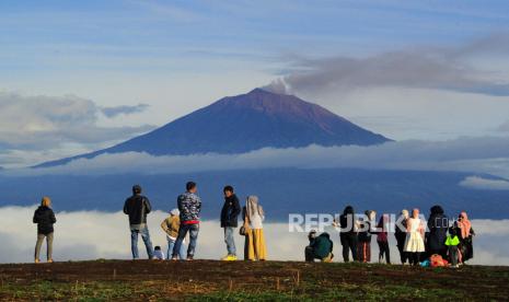 Pengunjung berada di tempat wisata Bukit Tirai Embun dengan latar Gunung Kerinci, Jambi (ilustrasi). Pusat Vulkanologi dan Mitigasi Bencana Geologi (PVMBG) melaporkan adanya aktivitas erupsi berupa lontaran kolom abu setinggi 200 meter di Gunung Kerinci di Jambi dan Sumatera Barat pada hari ini, Selasa (1/11/2022).